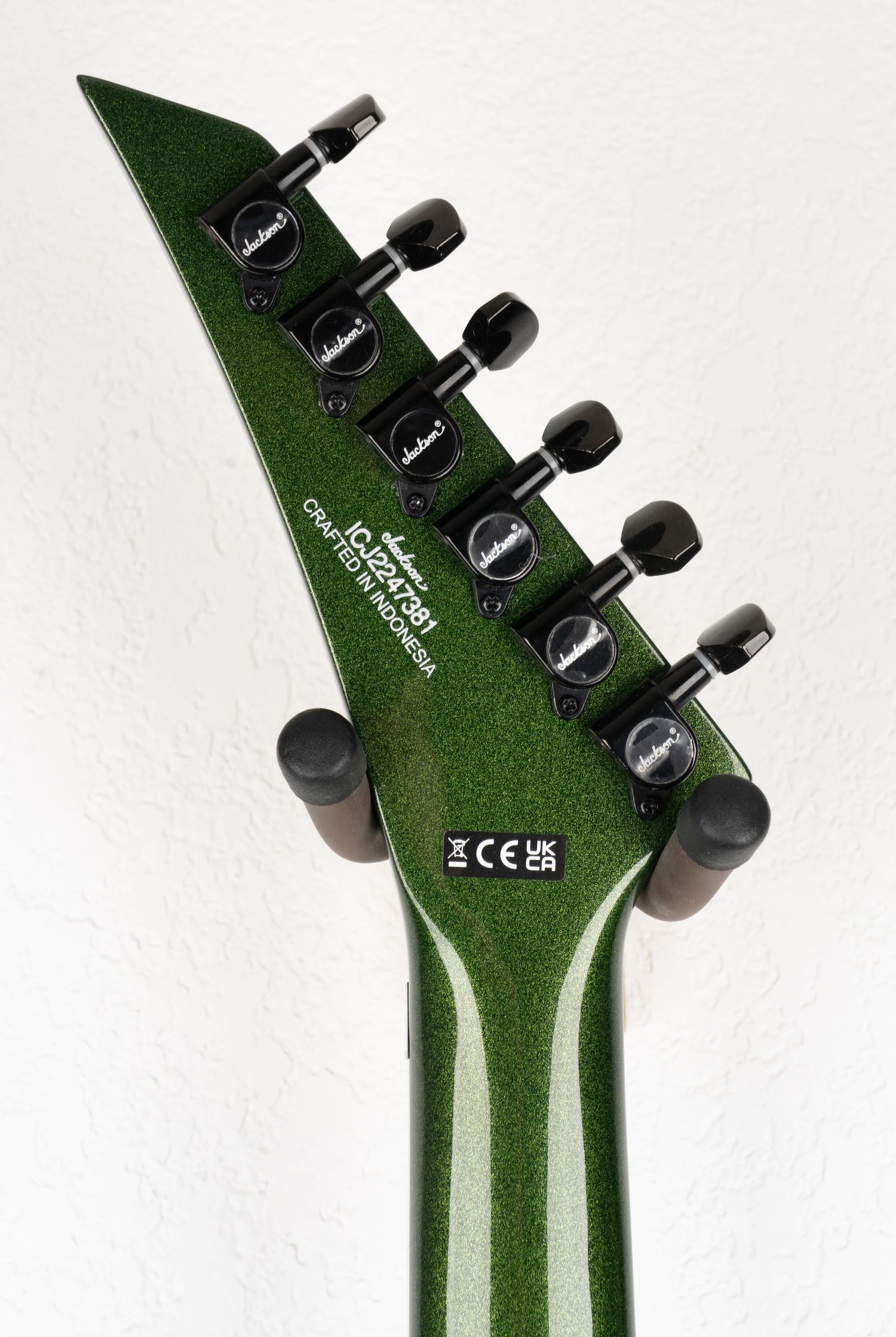 Green metallic Jackson guitar headstock with black tuning machines.