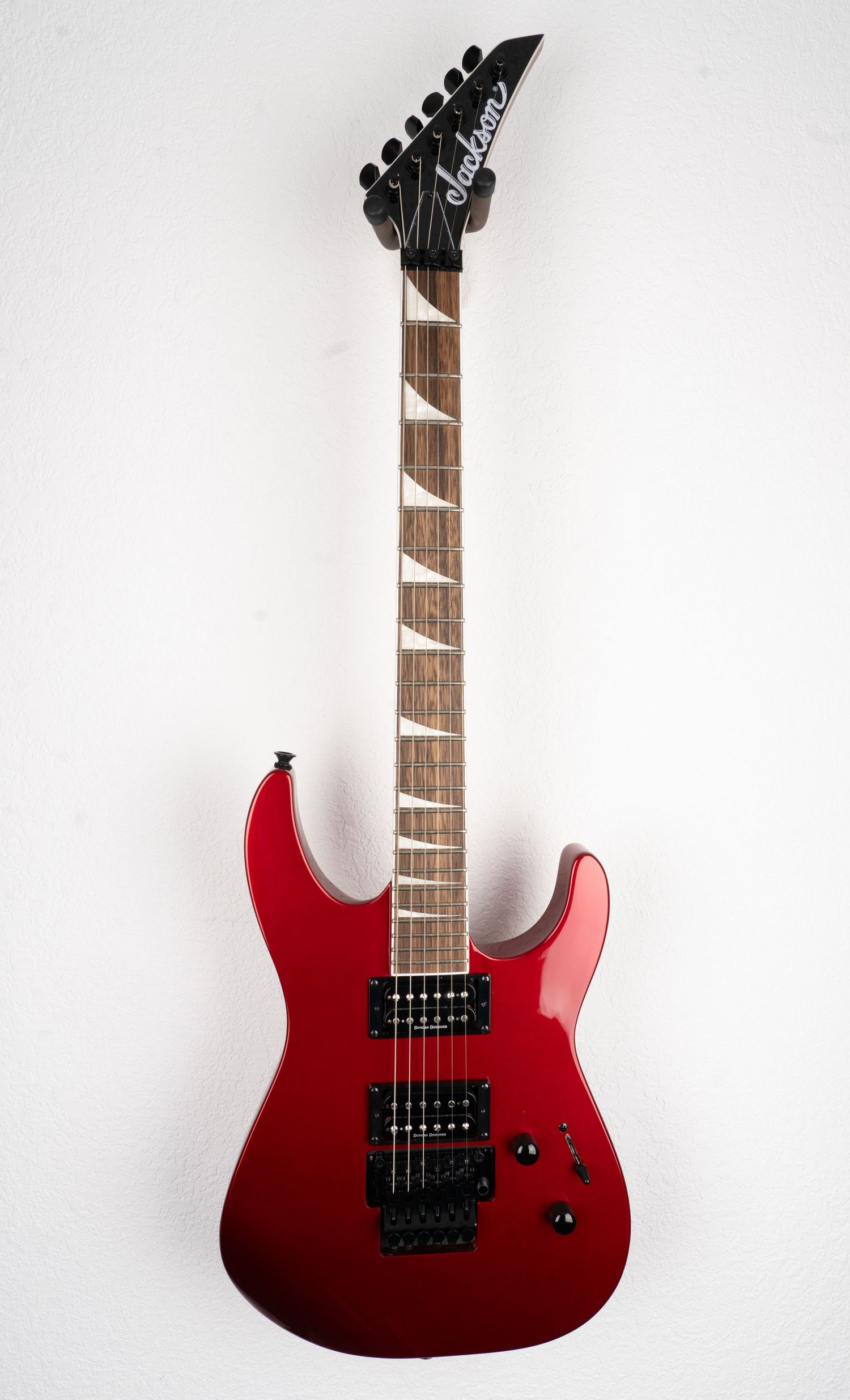 Red metallic electric guitar with dual humbuckers and Floyd Rose tremolo system.