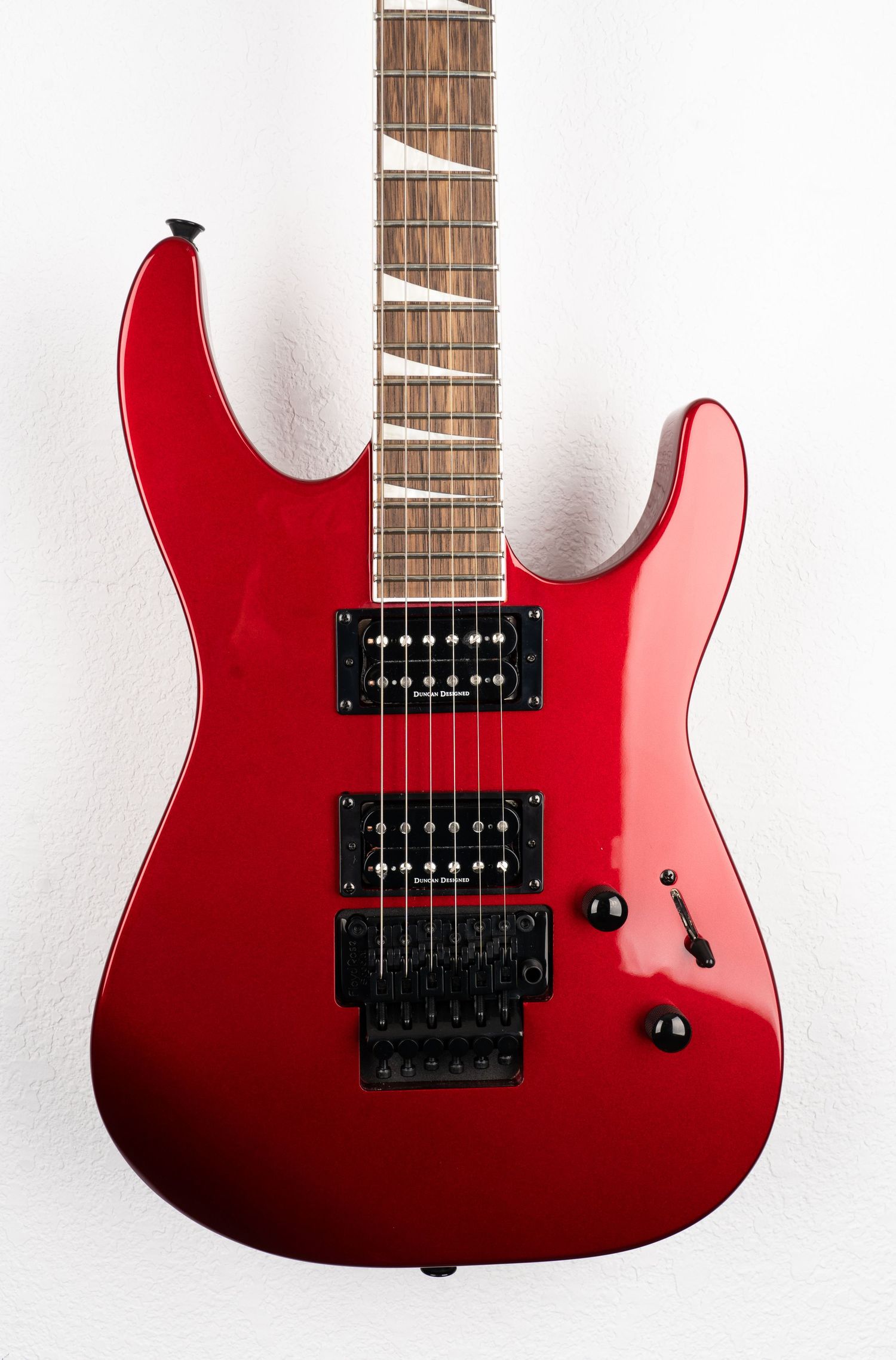 Red metallic electric guitar with dual humbuckers against white background.