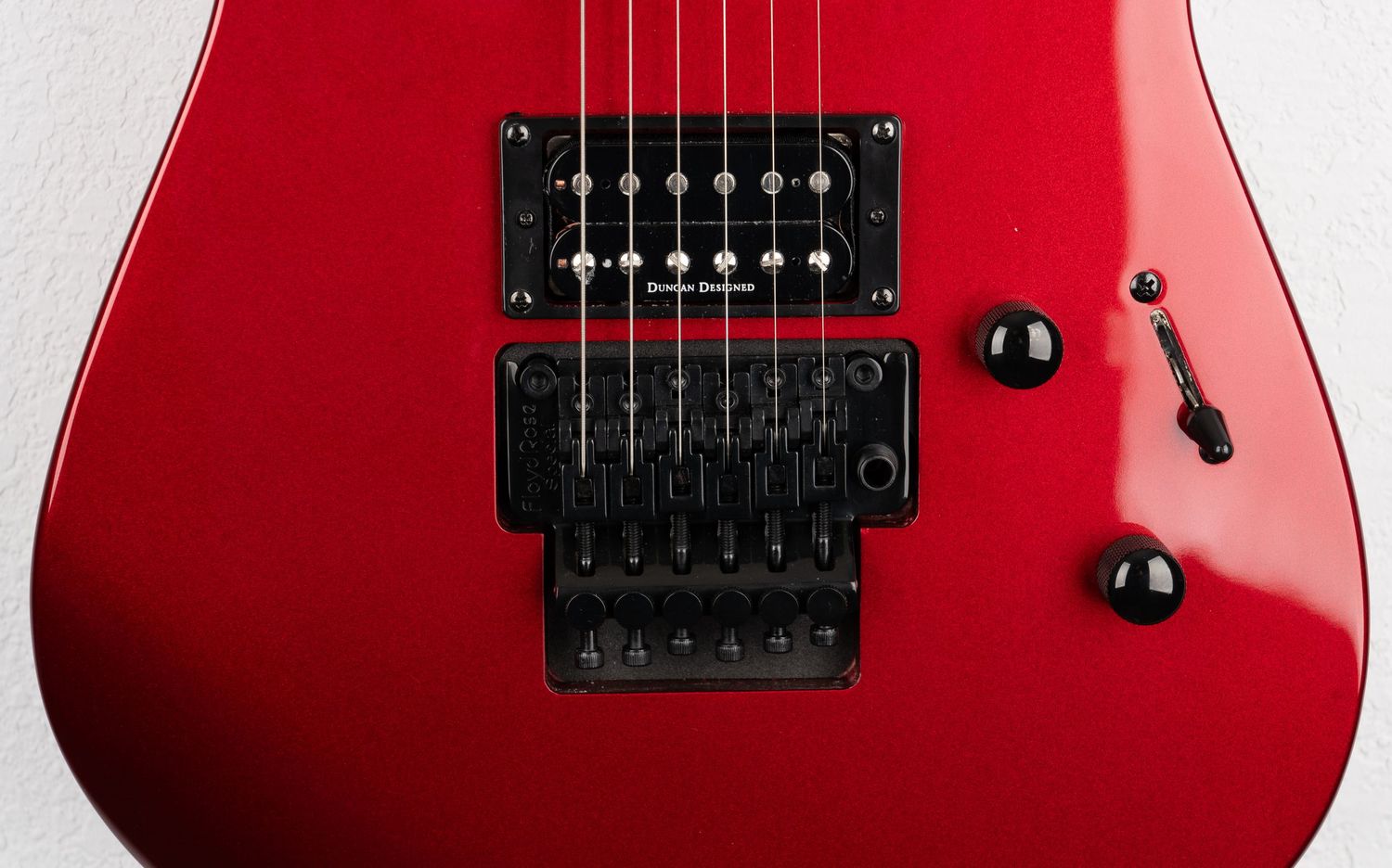 Close-up of a red electric guitar showing black humbucker pickups and hardware details.