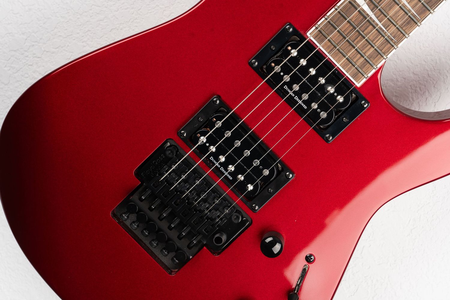 Detail shot of red electric guitar body showing dual humbuckers and bridge system.