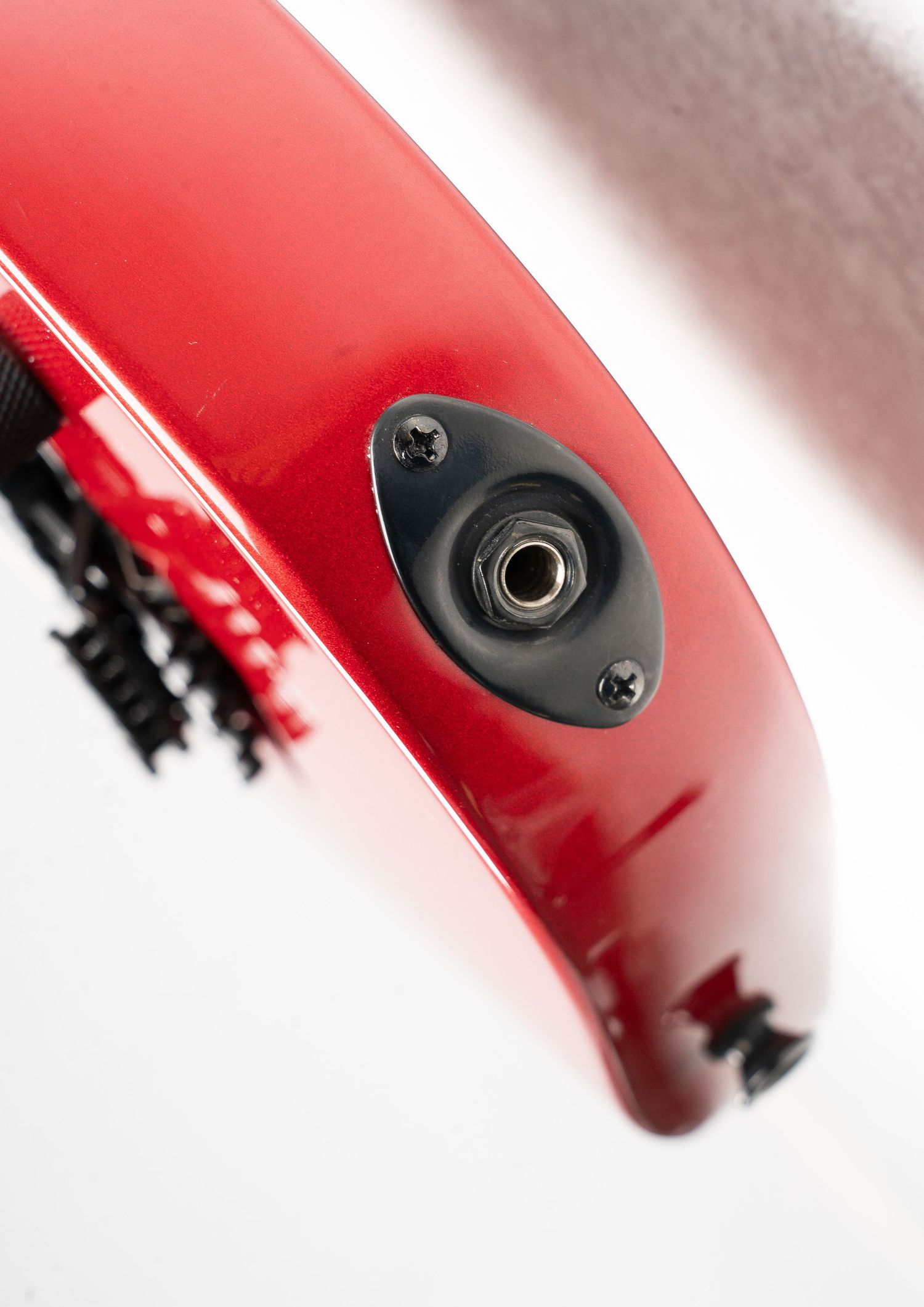 Close-up of a guitar output jack mounted on red finish body.