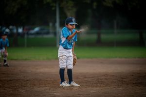 kid baseball player blowing dirt in his hand