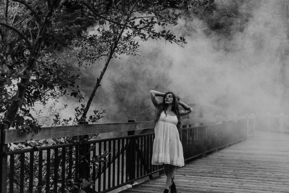 model poses on bridge with smoke in background