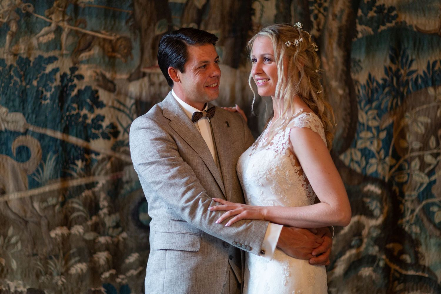 A tender moment between newlyweds against a decorative tapestry background.