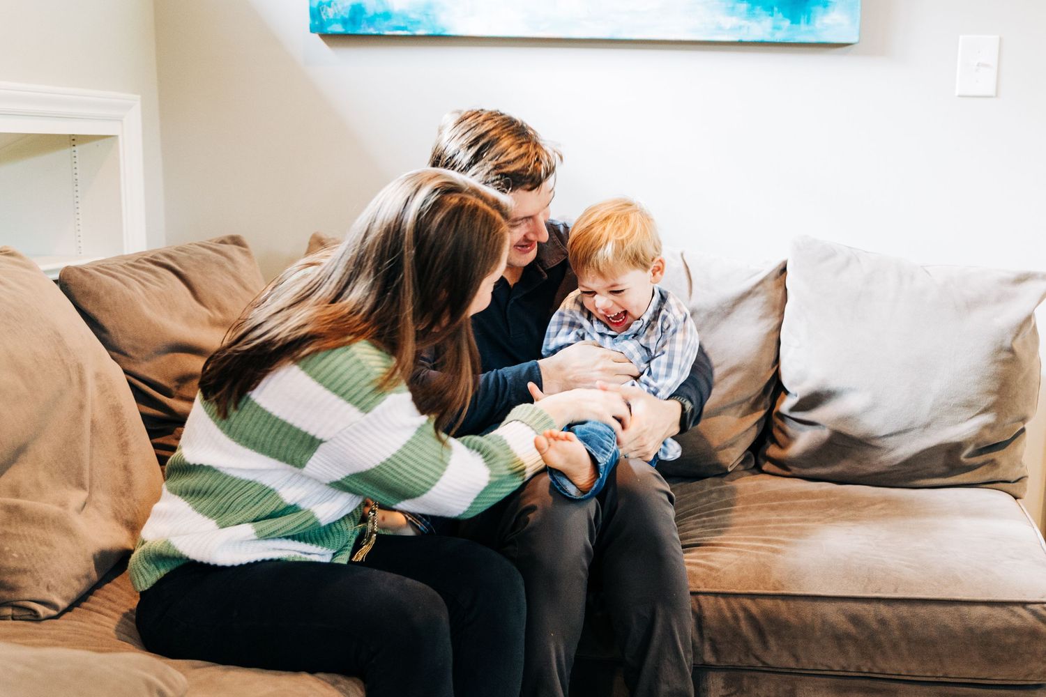 Family of 3 tickling on the couch