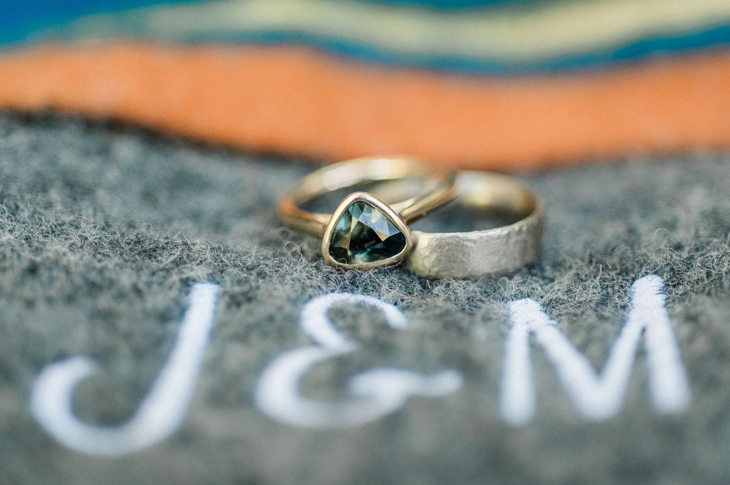 A close-up macro shot of  wedding ring with monogramed blanket with the initials J and M