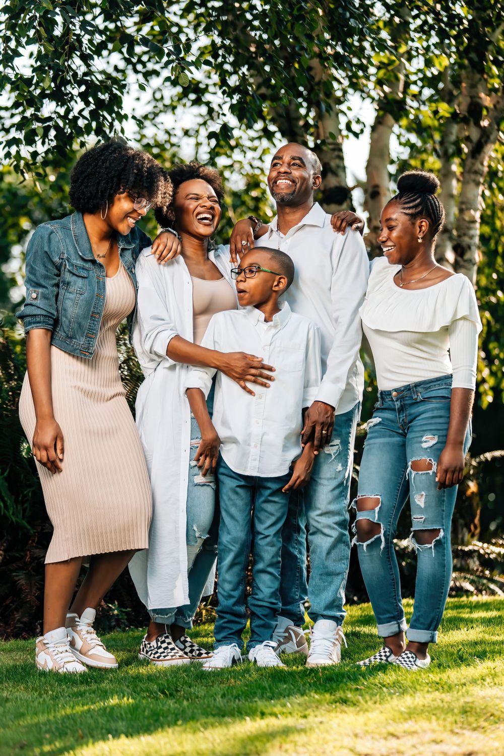 A candid family moment showing joyful laughter in casual outfits against trees.