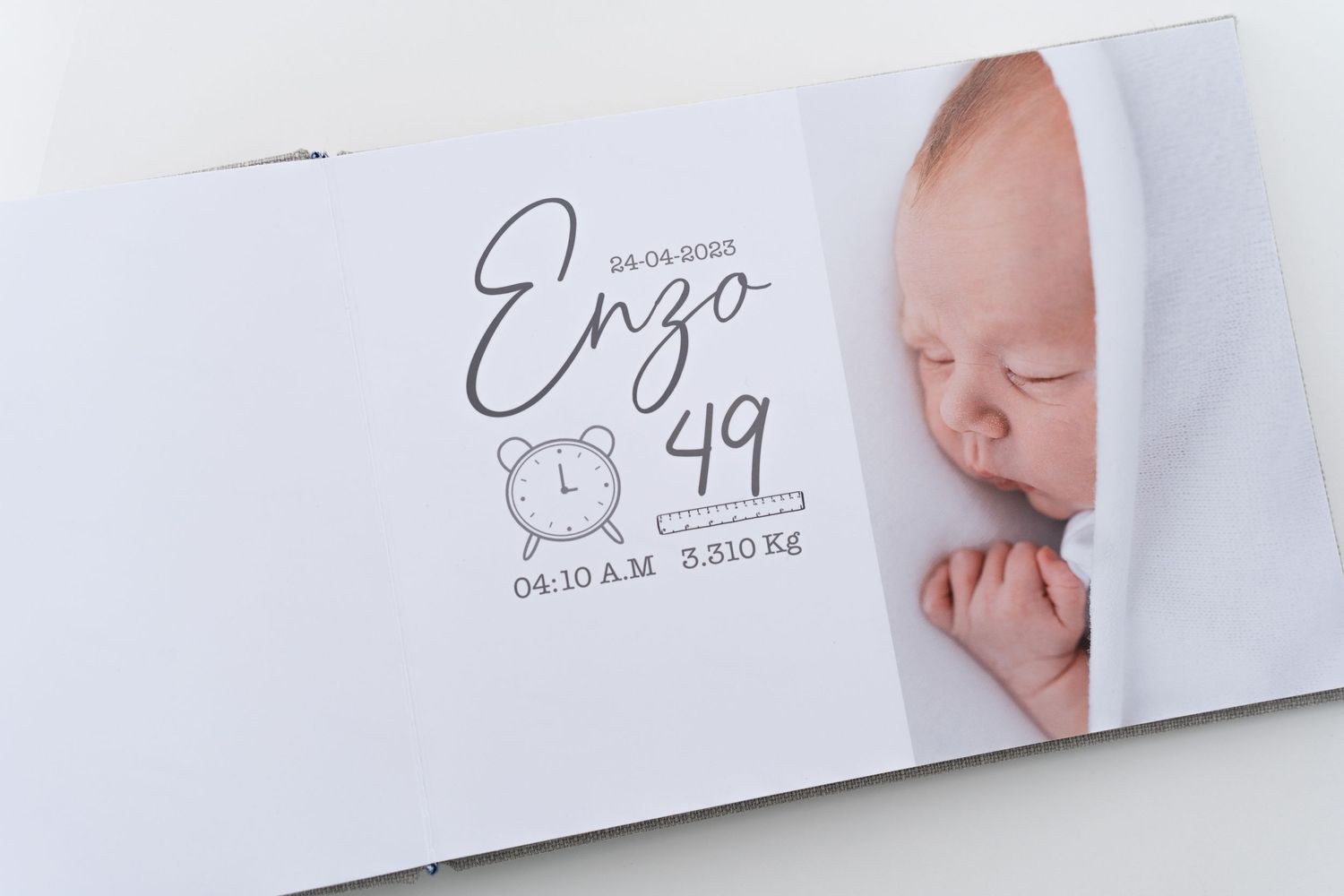 Delicate photo album page showing a sleeping newborn baby swaddled in white with handwritten text.