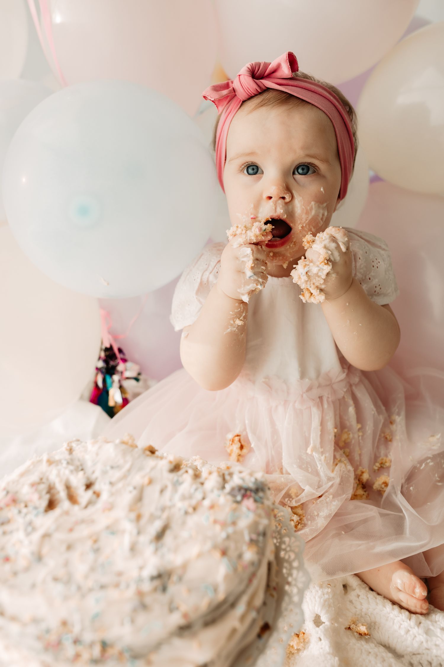 baby girl eating first birthday cake