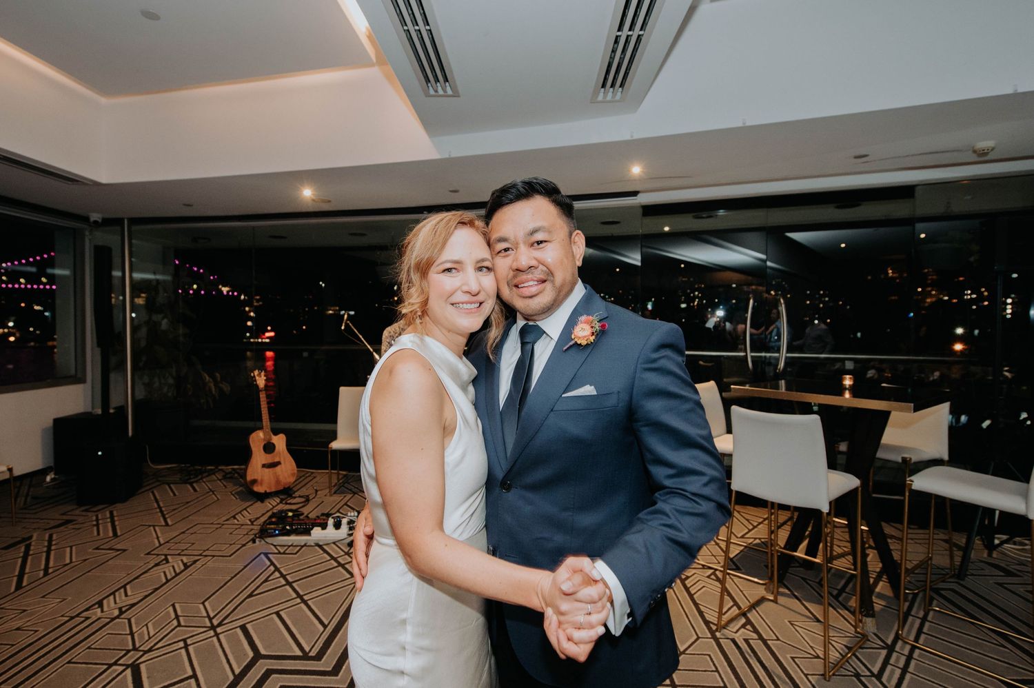 Couple shares romantic dance moment at indoor wedding reception venue.