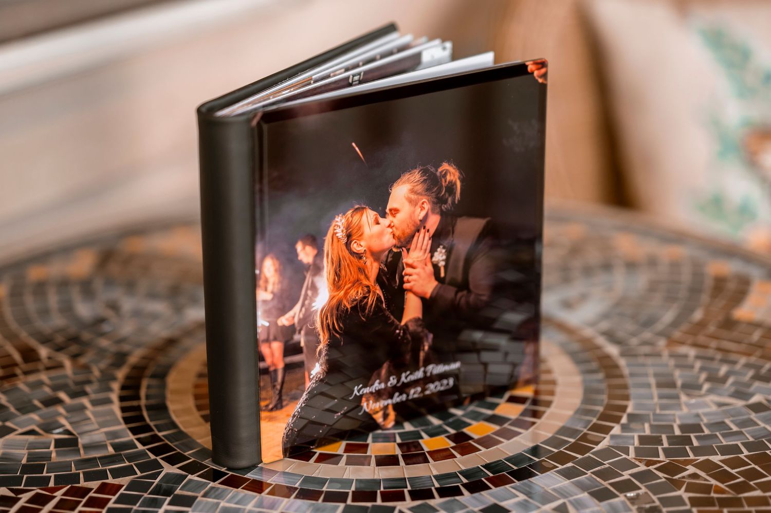 Dark leather photo album displayed on a mosaic table.
