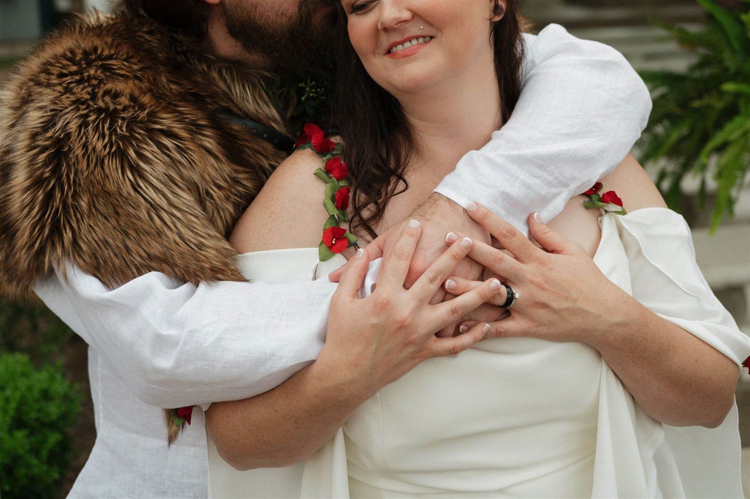 Close-up of hands embracing in romantic pose showing renaissance wedding attire details.