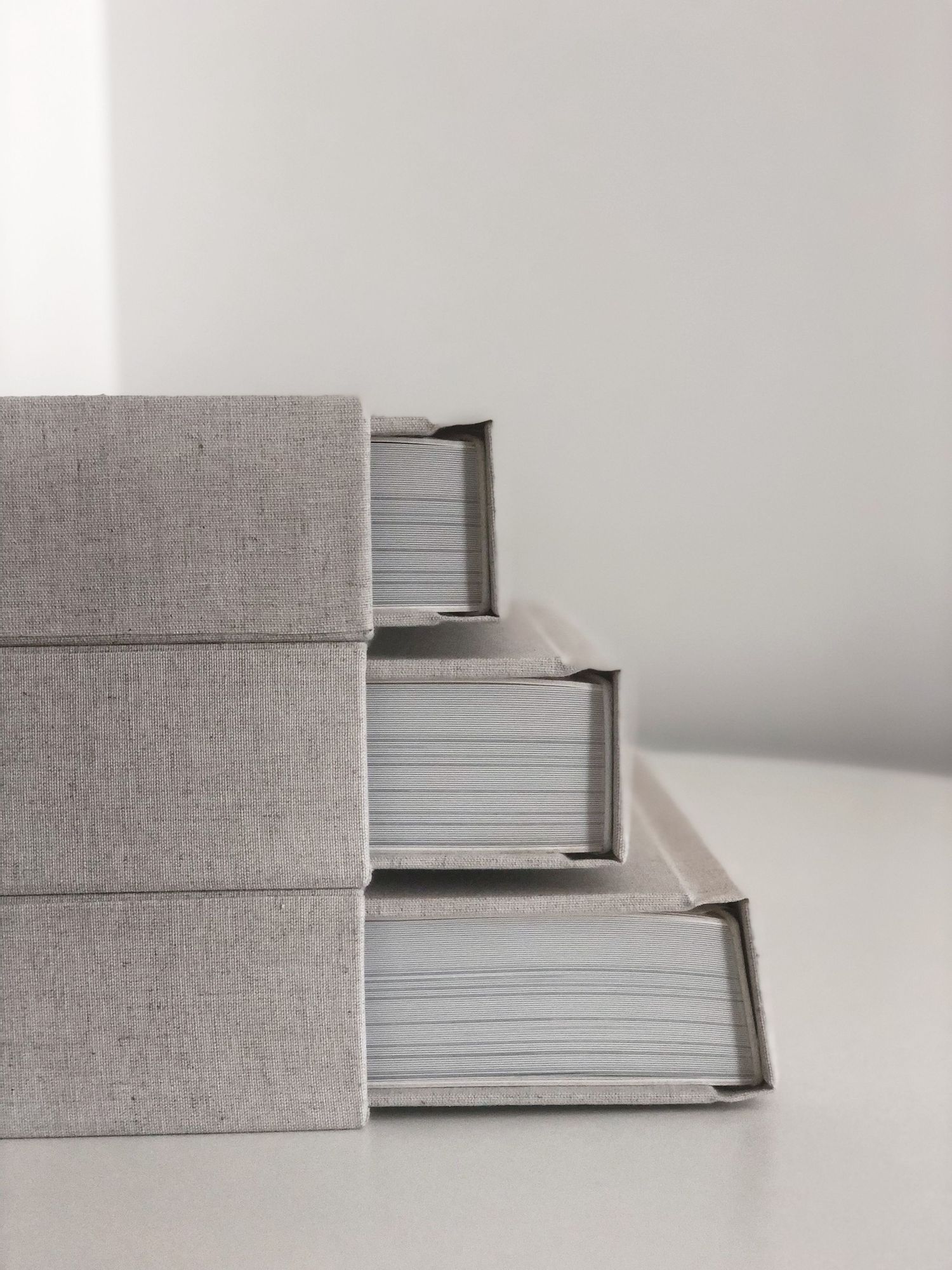Stack of three grey linen-bound photo albums on white surface.