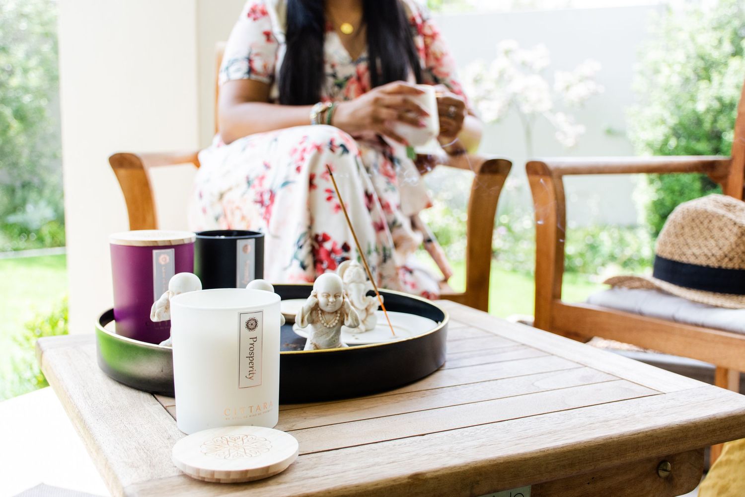 Skincare products and beauty items arranged on wooden tray with person in background.