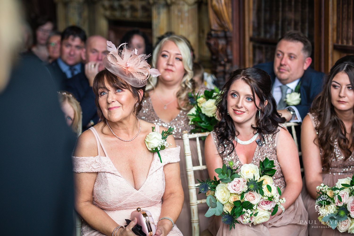 Emotional wedding ceremony moment with bridesmaids in pink dresses watching.