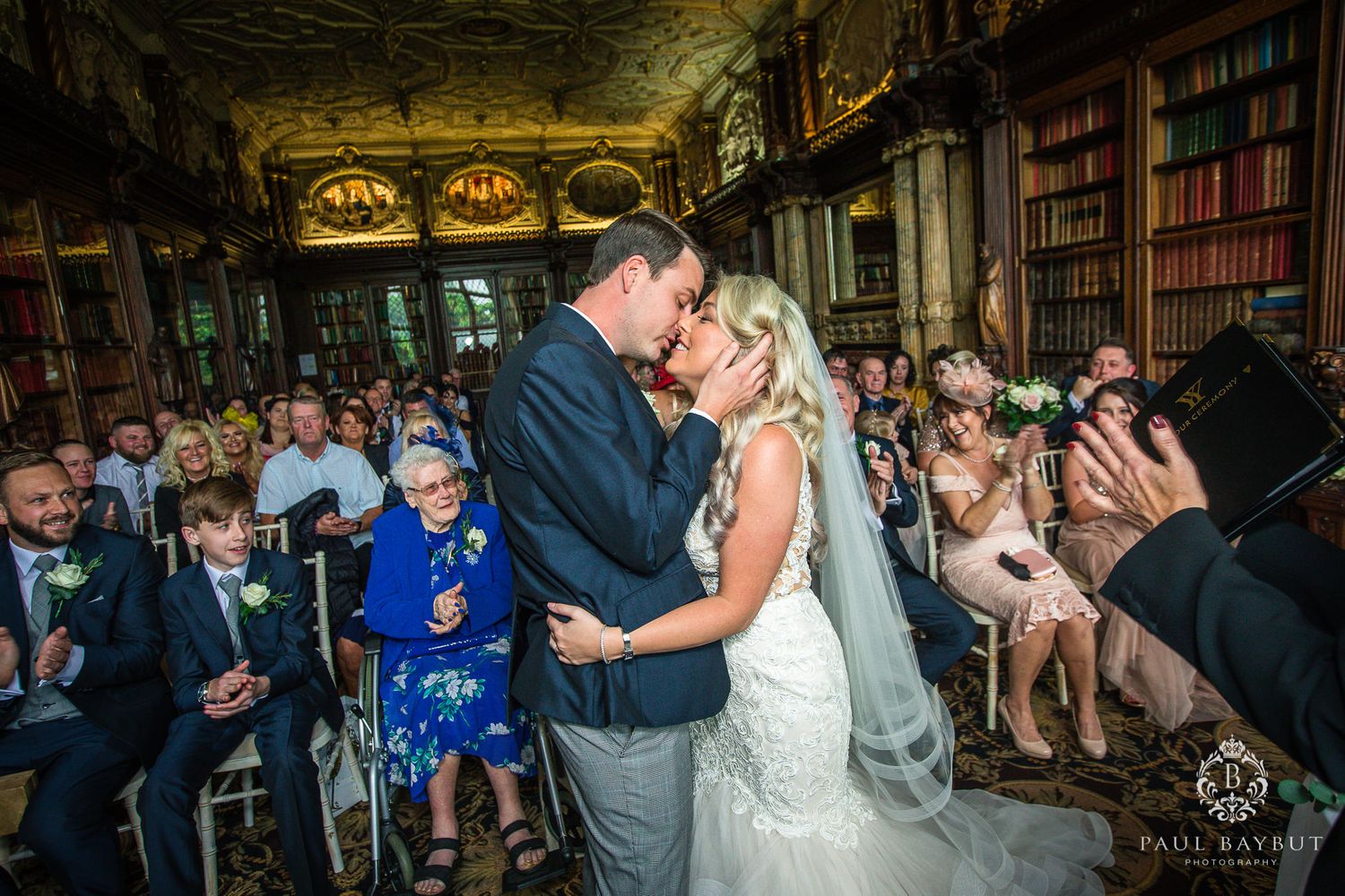 A romantic wedding moment captured in a historic library with wood paneling and vintage books.