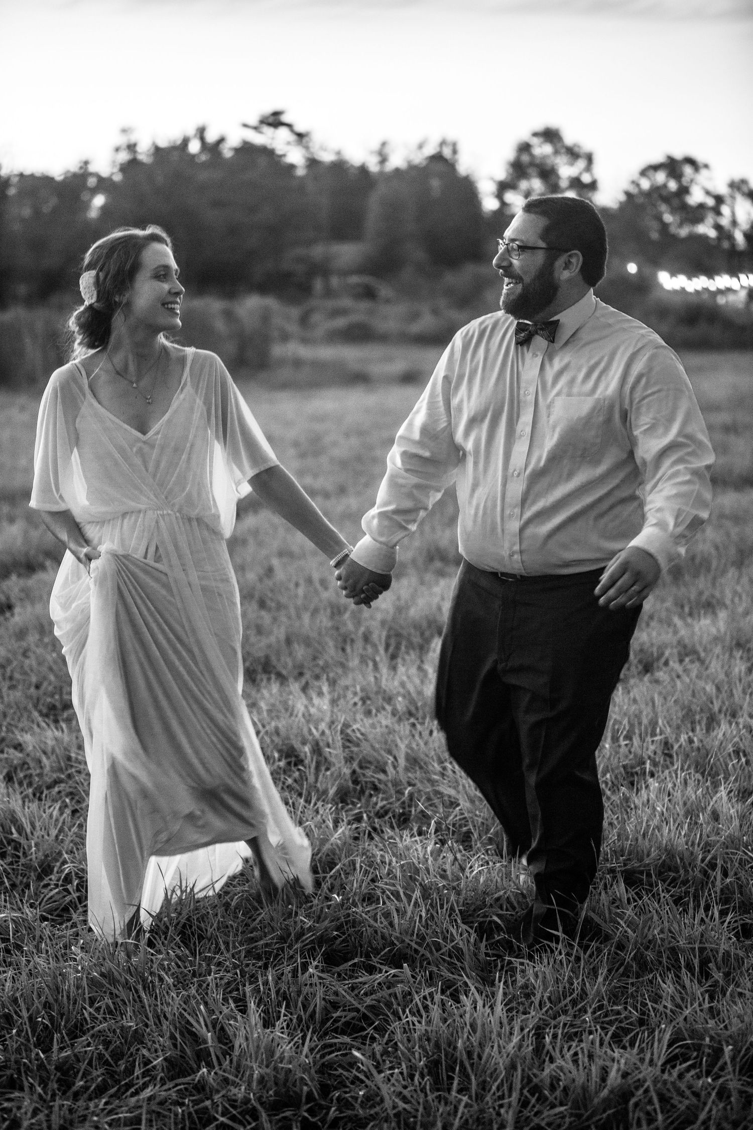 bride and groom in a field holding hands, in the style of  neopan, jewish culture themes, black and white portrait