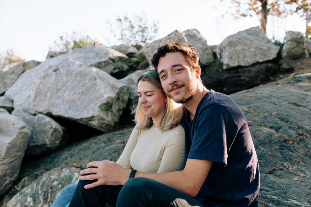 A couple shares an intimate moment while sitting together on rocky terrain.