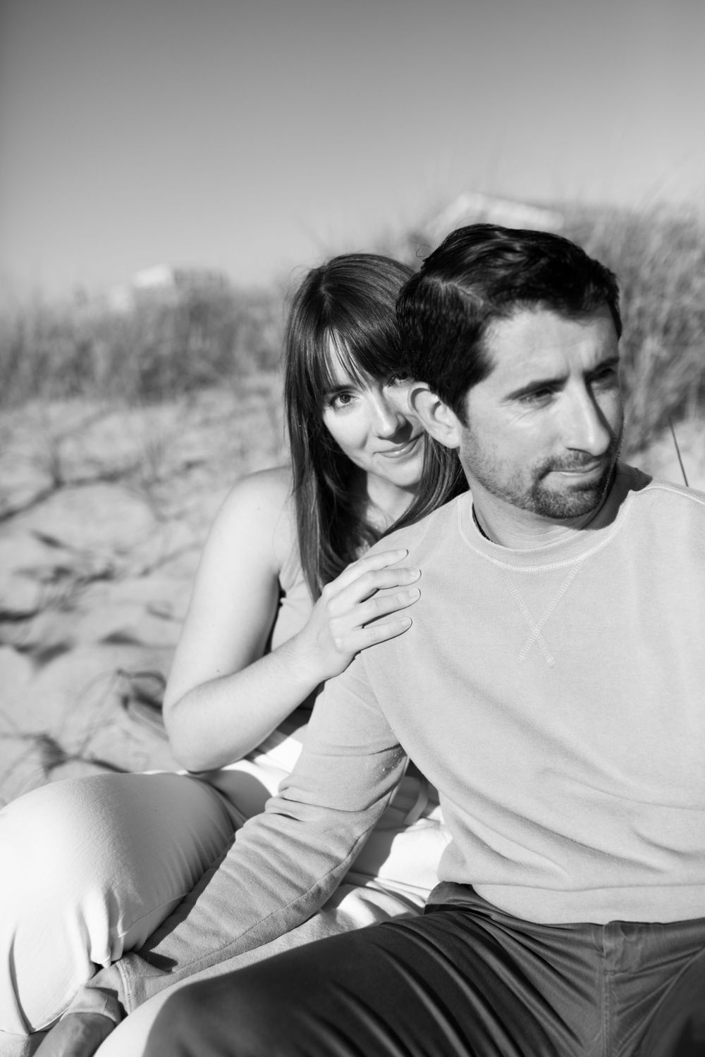 A couple shares a tender moment while sitting outdoors in black and white photography.