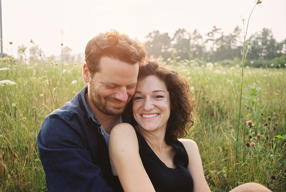 Joyful couple sharing close moment in sunny summer meadow.