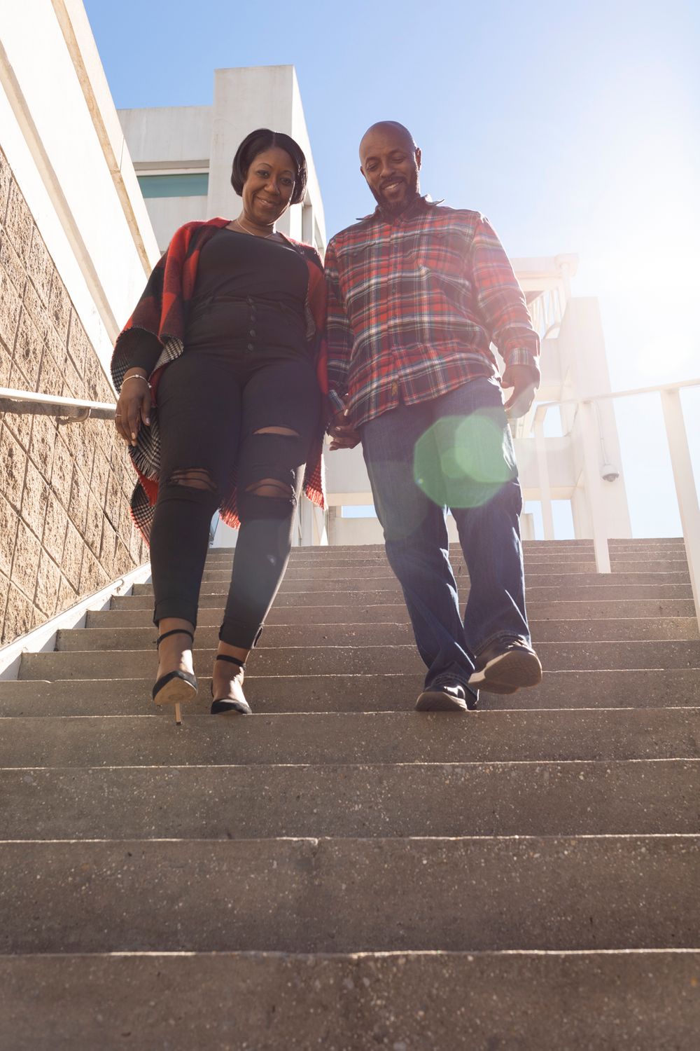 A couple holding hands and walking down the stairs.