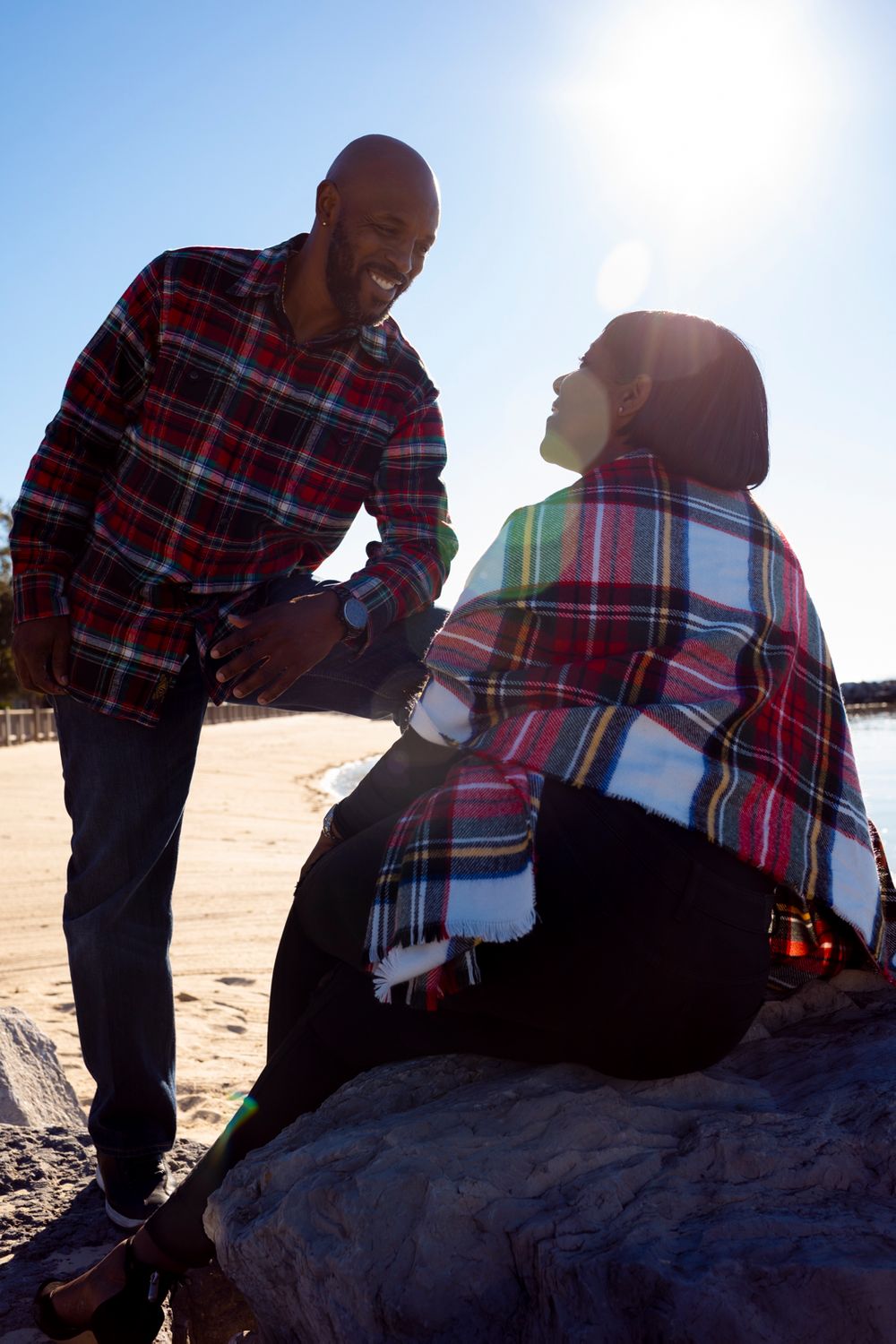 A couple looking at each other, one is sitting on a rock and the other is standing.