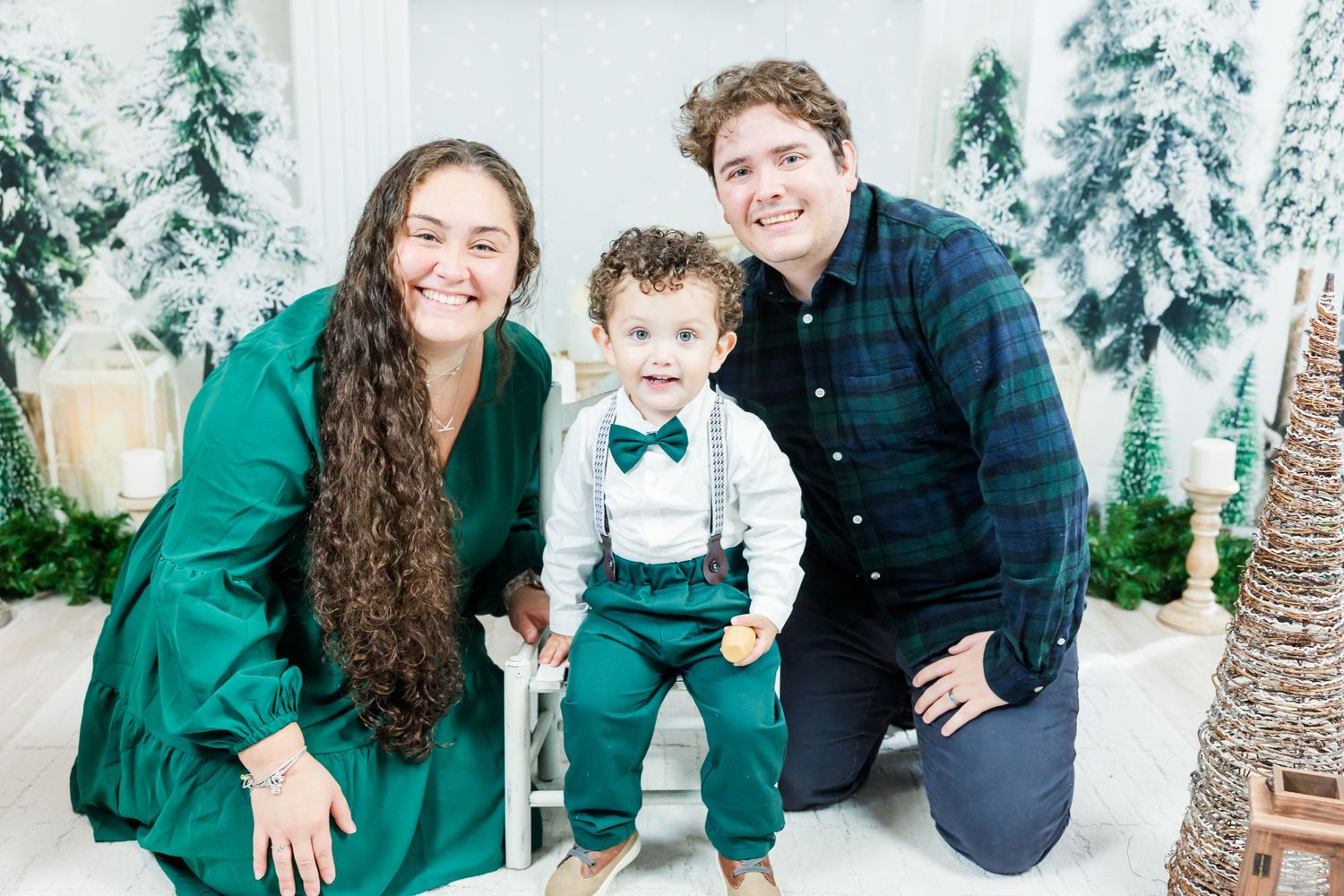 Holiday family portrait with winter wonderland backdrop and snow-covered trees.
