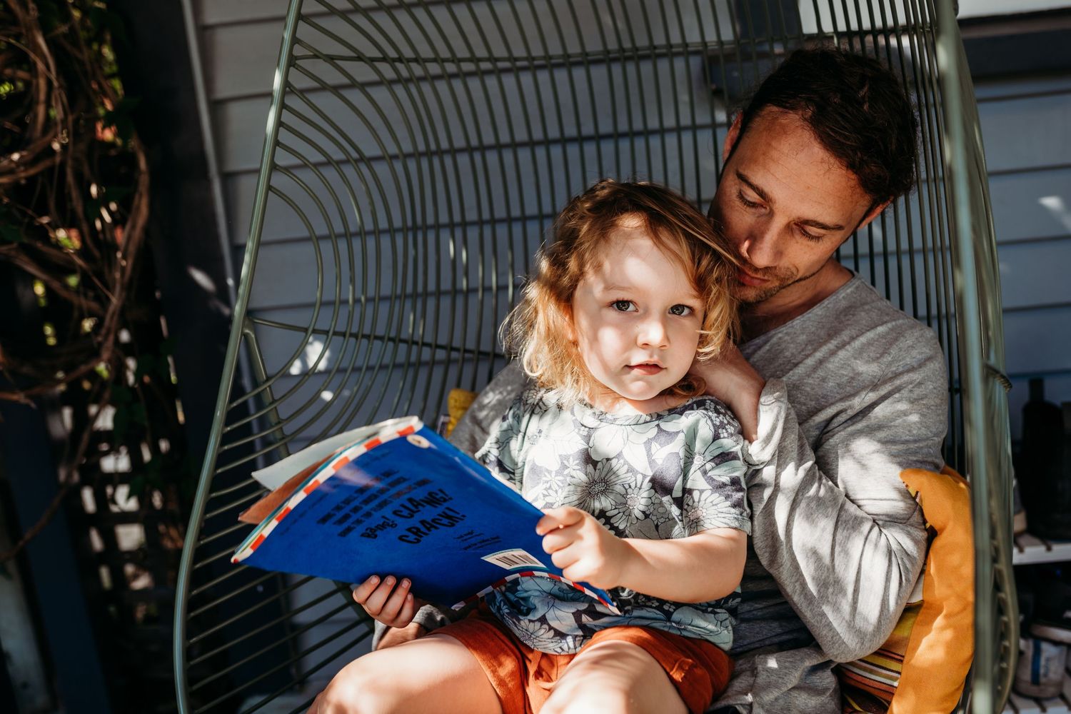 A shared reading moment in a cozy corner with a blue book and natural lighting.