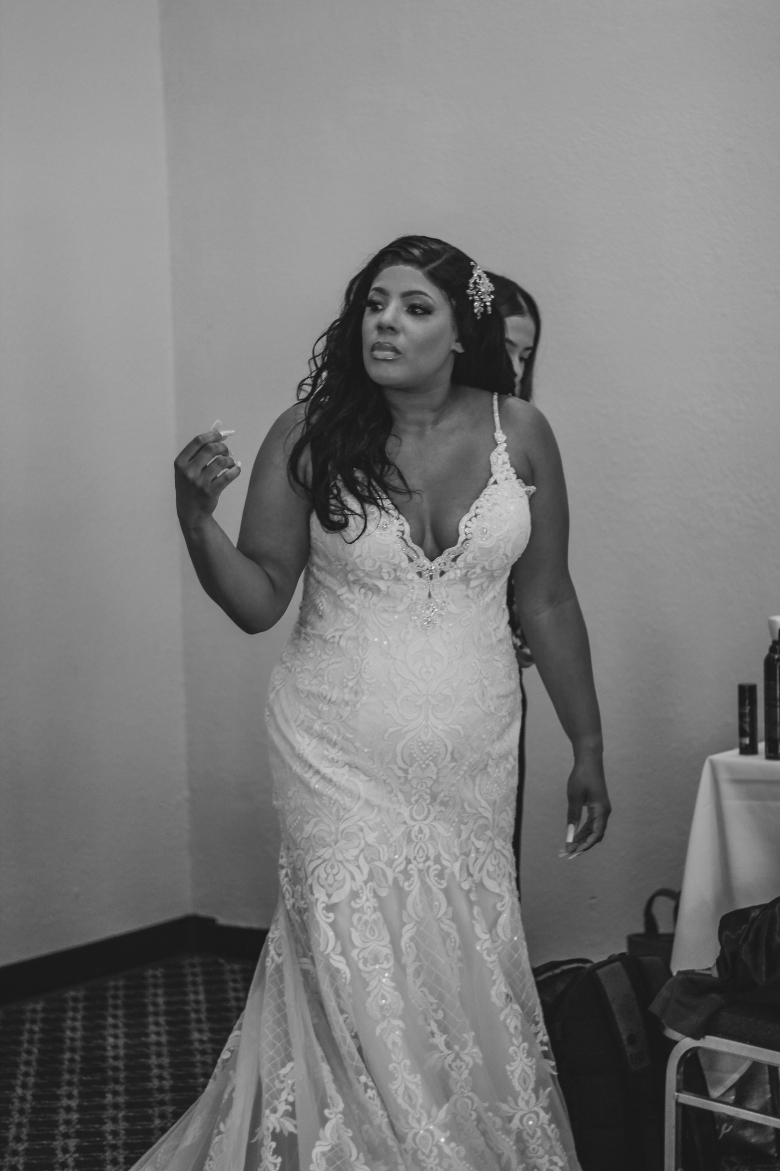 A bride shows off the details of her lace wedding gown in a series of black and white photos.