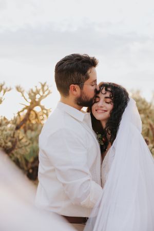 Close-up wedding portrait showing tender moment between newlyweds in desert setting.