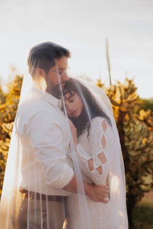 Ethereal wedding photo with flowing veil and soft desert lighting creating romantic atmosphere.