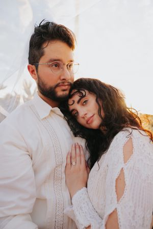 Romantic close-up portrait of newlyweds in white attire with soft natural lighting.