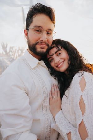 Tender wedding portrait showing couple in white embracing with gentle smiles.