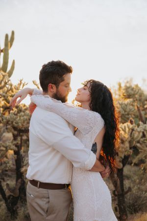 A romantic dance pose captured in a desert setting with saguaro cacti at sunset.