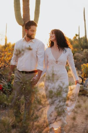 Romantic desert engagement photos with a couple walking among saguaro cacti at golden hour.