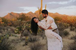 Romantic desert photoshoot with mountains and saguaro cacti during golden hour.