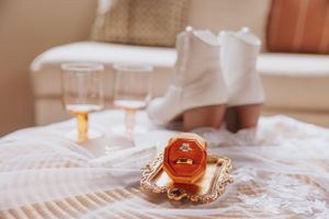 Wedding accessories including white shoes and brown leather details laid out on a neutral surface.
