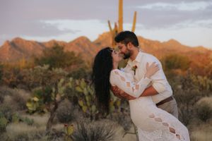 Couple embracing during sunset in a scenic Sonoran Desert landscape with mountains.