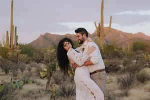 Romantic photoshoot in the Sonoran desert with dramatic mountain backdrop and golden hour lighting.