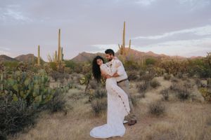 Couple shares tender moments in a desert setting with iconic saguaro cacti silhouettes.