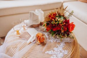 Elegant table setting with vibrant orange and red floral arrangements on a woven placemat.