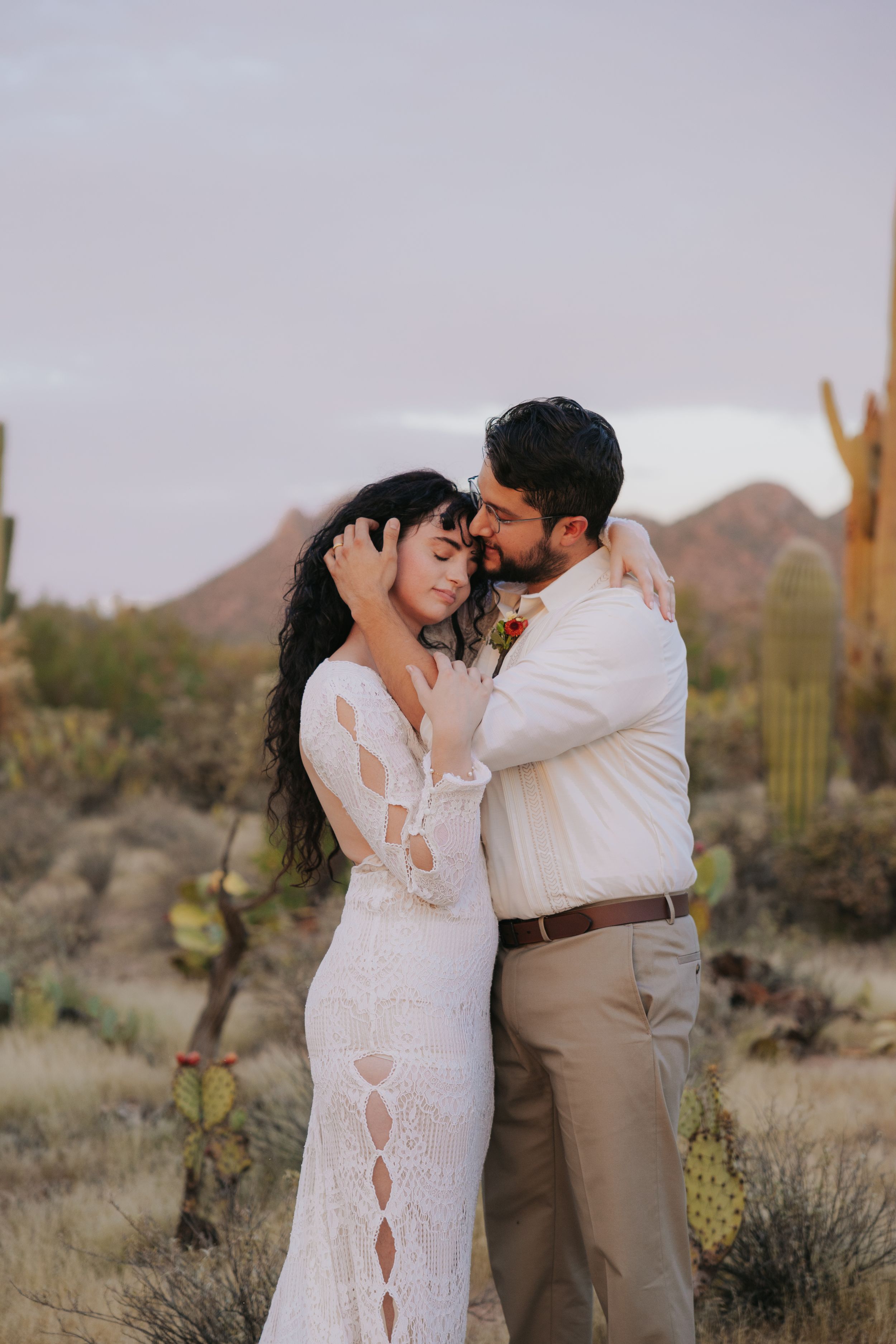 Desert romance captured in an intimate moment with saguaro cacti and mountains in view.