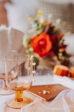 Orange glassware and floral arrangements on a rustic table setting with warm lighting.