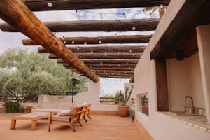 Rustic wooden pergola with string lights creating an outdoor seating area.