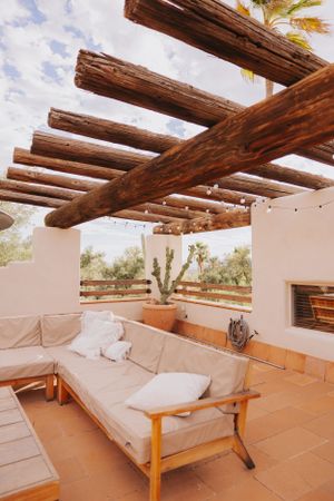 Desert-style patio with exposed wooden beams and comfortable cream-colored seating.