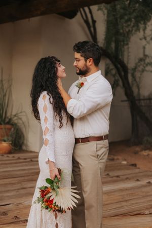 Wedding ceremony at a rustic desert venue with white walls and wooden beams.