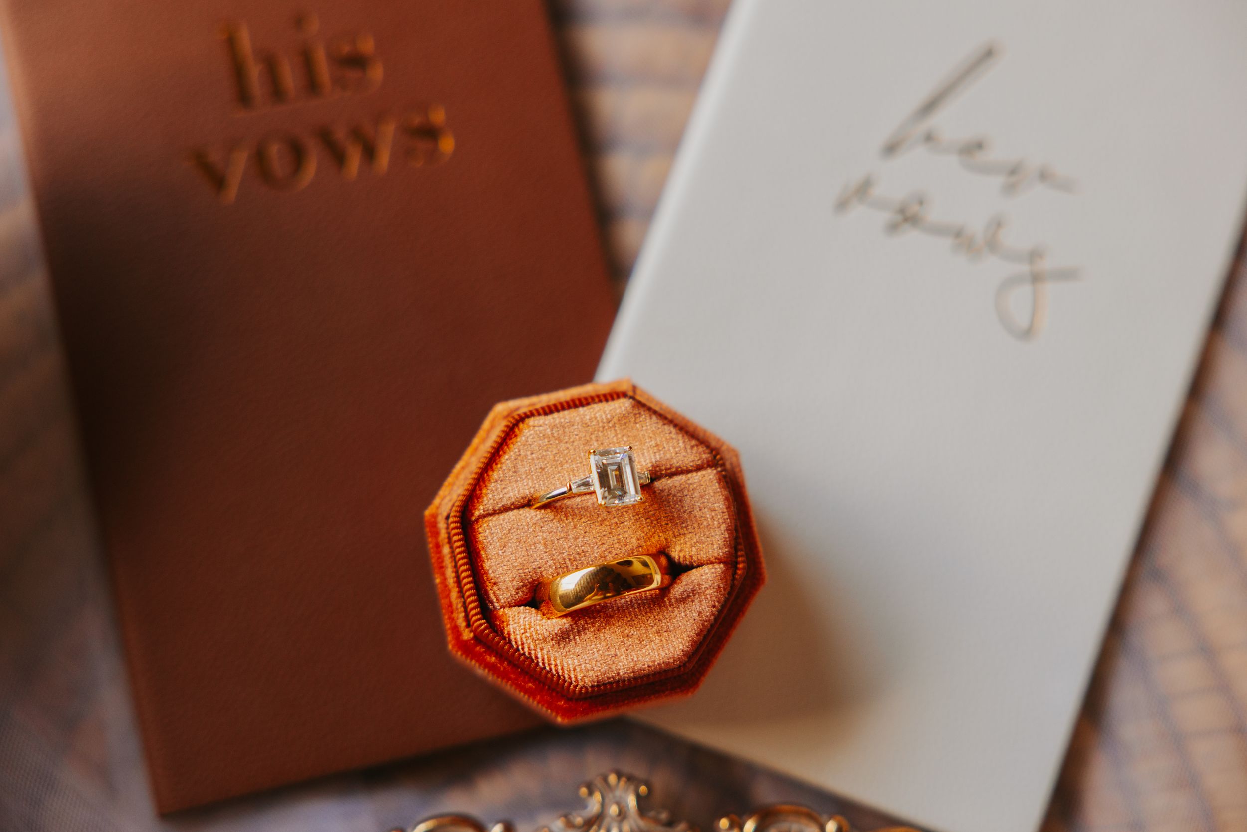 Wedding vow books and decorative gold tray with wax seal on wooden surface.