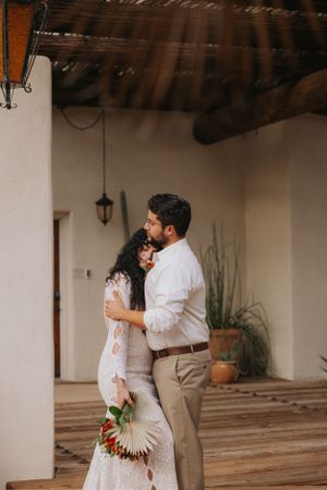 Intimate wedding moment under rustic wooden beams at desert venue.