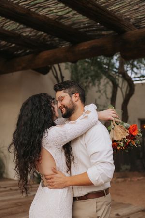 Romantic wedding dance under wooden beams at desert venue.